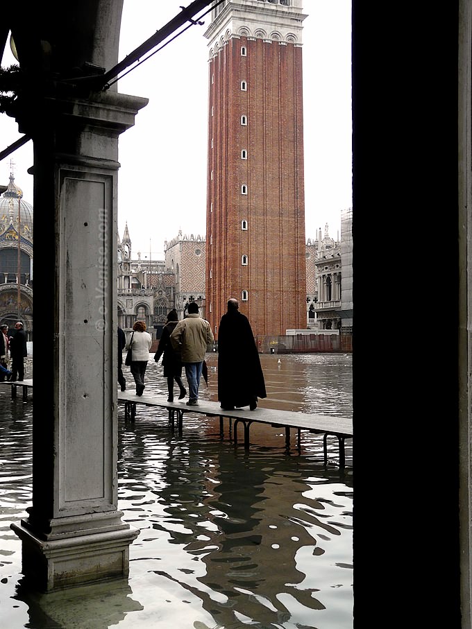 prêtre se rend à Saint Marc en empruntant la passerelle piétons pour l'acqua alta
